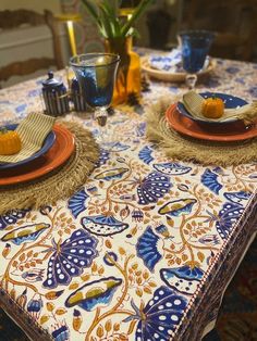 the table is set with blue and orange plates, napkins, and place mats