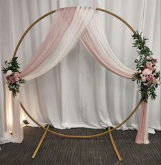 a wedding arch decorated with pink flowers and greenery