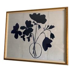 a painting with flowers in a vase on the wall above it is hanging from a wooden frame