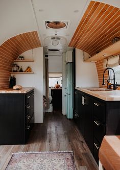 the interior of an rv with wood flooring and black cabinets, along with a rug