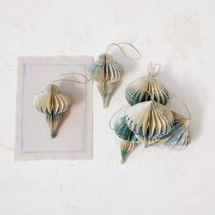 three seashells are hanging from twine strings on a white surface with a blue square