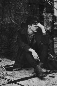 a man sitting on the ground next to a tree