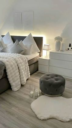 a bedroom with white walls and wood flooring is pictured in this image, there are candles on the side table next to the bed