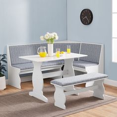 a white table with two benches next to it and a clock on the wall behind it