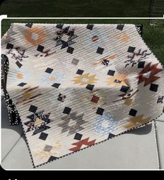 a quilted blanket sitting on top of a metal bench