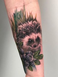 a hedgehog tattoo on the arm with roses and leaves around it's head