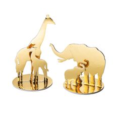 two giraffes and an elephant are standing on gold bases with their trunks in the air