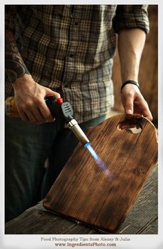 a man is using a lighter to light up a wooden cutting board with a lighter in it