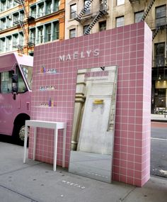 a pink food truck parked next to a building with a door on it's side