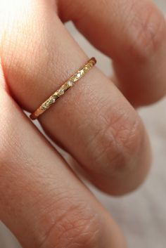 a woman's hand with a gold ring on her left hand and diamond band