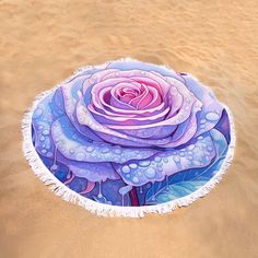 a round beach towel with an image of a pink rose in the middle of it