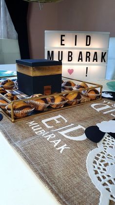 a table topped with muffins on top of a brown rug next to a lit sign