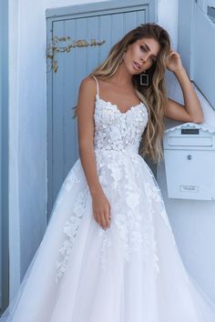 a woman in a white wedding dress leaning against a wall with her hand on her head