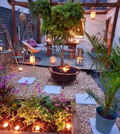 an outdoor patio with candles lit up in the center and potted plants on the other side