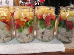 four mason jars filled with different types of veggies on top of a counter