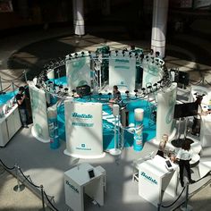 people are standing around in front of an exhibition stand with blue and white displays on it