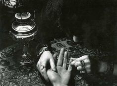 two hands with arabic writing on them are touching each other's fingers in front of an ornately decorated table