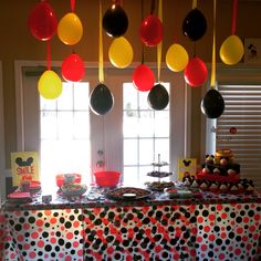 a table topped with lots of different types of balloons hanging from it's ceiling