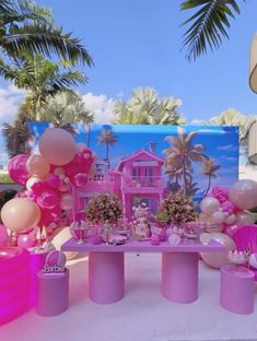 a table topped with lots of pink and white balloons in front of a palm tree