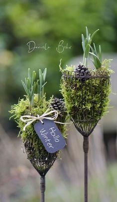 two metal planters with moss and pine cones tied to them