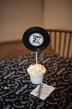 a bowl of popcorn sitting on top of a table next to a sign that says two people