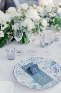 the table is set with wine glasses and place cards