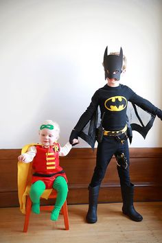 two children dressed up as batman and robin wayne sitting on a chair with the caption happy halloween