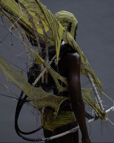 a woman in yellow is holding a large piece of wire