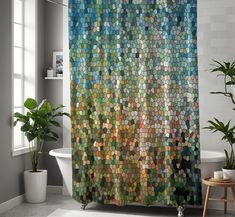 a bathroom with a shower curtain covered in multicolored tiles and potted plants