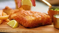 a wooden cutting board topped with fish and fries