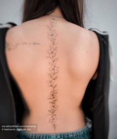 the back of a woman's neck with tattoos on it and flowers growing out of it