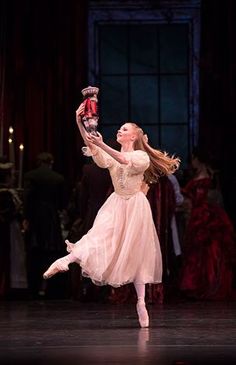 a ballerina in a pink dress is holding a nutcracker