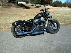 a black motorcycle parked on the side of a road next to a grass covered field