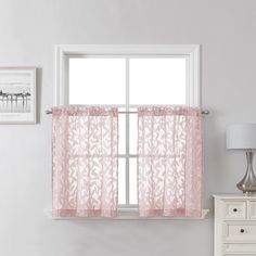 a window with a pink curtain hanging from it's side next to a white dresser