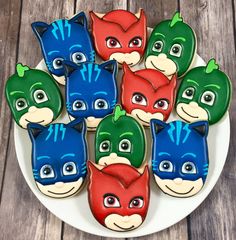 some decorated cookies are on a plate with the faces of batman and catwomans