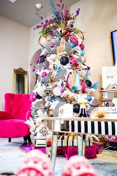 a decorated christmas tree in the middle of a living room with pink chairs and other decorations