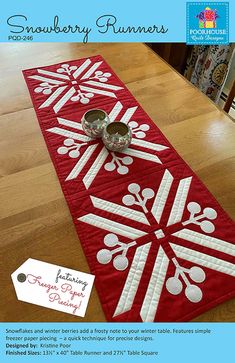 a red table runner with white snowflakes on it and two silver cups sitting on top