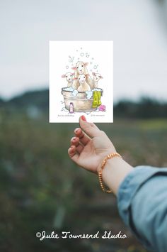 a person holding up a card with two bears in a bathtub on top of it