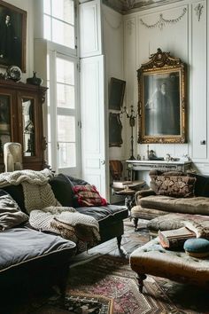 a living room filled with lots of furniture and paintings hanging on the wall above it