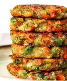 a stack of vegetable fritters sitting on top of a white plate covered in sauce