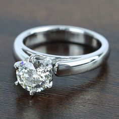 a close up of a ring with a diamond on it's shants, sitting on a wooden surface