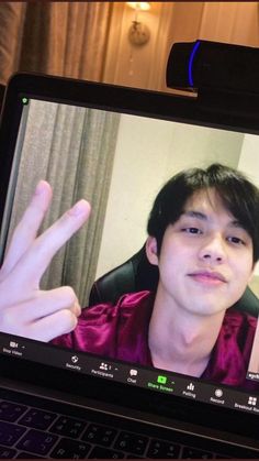 a person is on a laptop screen with the image of a young man making a peace sign