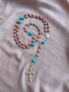 Handmade Rosary infused with love and prayer! 8mm Orange Calcite - Hail Mary Beads 10mm Mint Turquoise - Our Father Beads Austrian Quartz Spacer Beads Italian Made Crucifix and Centerpiece Rosary Length - 24" Please note there is 2 Rosaries Available.  Option 1 has "Radiant Crucifix" Option 2 has "Filigree Crucifix"  Each rosary is handmade and infused with love and prayer throughout the whole process. Your rosary will come carefully wrapped in a box with padding for safe shipment.  You will als Gift Rosary With Round Natural Stones, Round Beads Rosary With Natural Stones For Gift, Bohemian Rosary With Natural Stones For Gifts, Turquoise Rosary With Round Beads, Spiritual Turquoise Rosary With Round Beads, Bohemian Beaded Rosary For Healing, Turquoise Rosary With Round Beads As Gift, Rosary Guide, Infused With Love