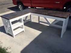 a bench and table sitting in the middle of a parking lot next to a red truck