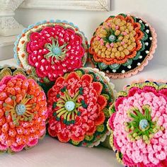 several crocheted flowers sitting on top of a white table next to a mirror