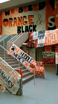 an orange and black banner is hanging on the wall next to some stairs in a building