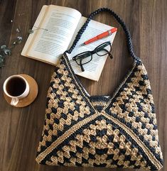 a crocheted purse sitting on top of a wooden floor next to an open book