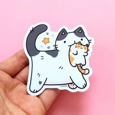 a hand holding a sticker with a cat on it's back and stars in the background