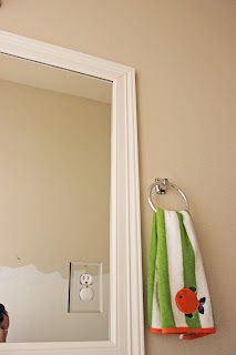 a bathroom mirror with a towel hanging on the wall