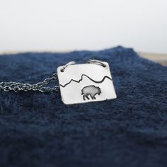 Bison Mountain Necklace In the West, we understand the magic of daring to wander freely. Let this Bison Mountain Necklace be your reminder to roam like you mean it – with courage, determination, and the untamed spirit that defines the true adventurer. Lead-Free Pewter 1" long x 3/4" tall Choose Your Chain Length Crafted with the same passion that drives us at Pure Impressions Design, our Mountain Jewelry pays homage to the vast mountains that touch the heavens.Handmade with love in the heart of Bison Ring, Bison Necklace, Delicate Montana Necklace, Sterling Silver Wolf Necklace, Mountain Jewelry, Mountain Necklace, Chain Lengths, Handmade Necklaces, Handmade Jewelry